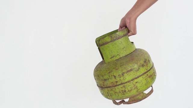 A person's hand is holding a 3 kg LPG gas cylinder. LPG gas is used as fuel for stoves.