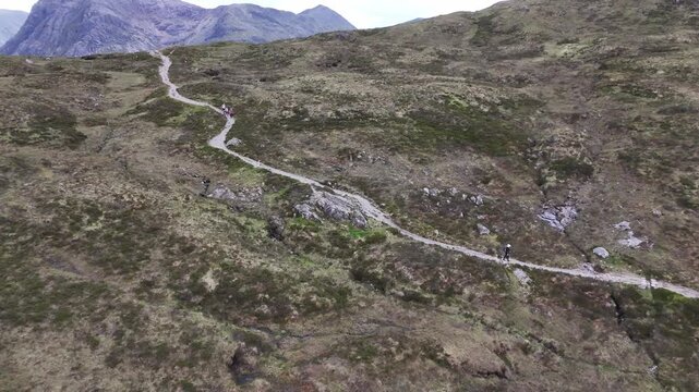 Aerial drone push back boom up shot of a hiker on the West Highland Way in Scotland. He walks down towards Kinlochleven after climbing the Devil's Staircase.