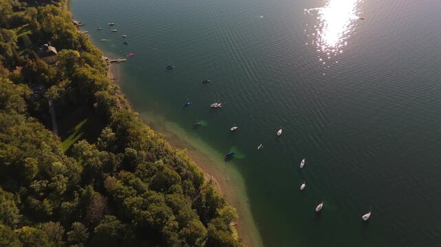 Autumn aerial view of Lake Starnberg (Starnberger See, formerly Wuermsee) near Munich in Bavaria Germany showing the forested coastline with fall colors and small boats anchored in clear calm water