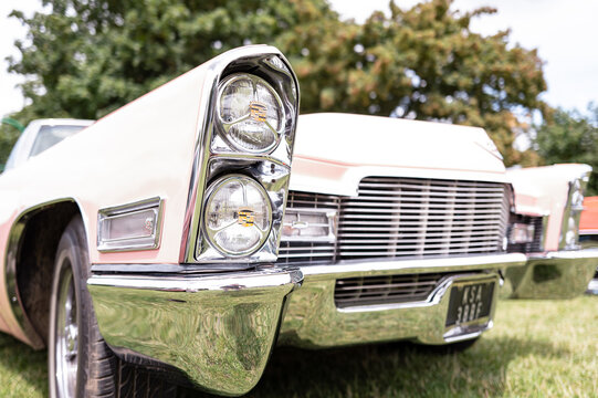 Detailed headlight view of a classic American Pink Cadillac showing the stacked headlights and detailed chrome work.