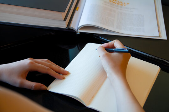 ノートにメモを書く女性の手元。ビジネス。学生