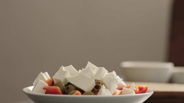 Close-up Greek salad in white bowl with stacked feta and olives