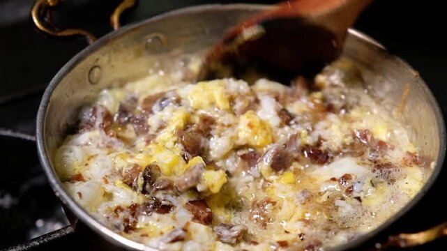 Kavurma and eggs cook together in a copper pan. Close-up scene showing Turkish breakfast presentation, a hot pan dish and traditional eggs with kavurma preparation.