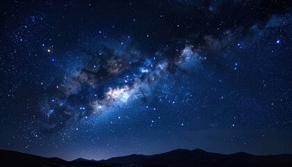 Fototapeta premium A breathtaking view of the Milky Way galaxy stretching across the dark night sky above silhouetted mountains.