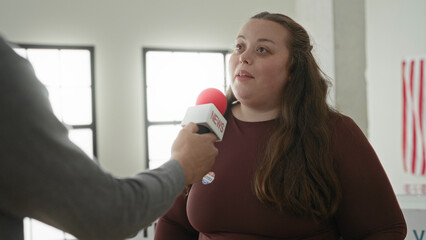 Fototapeta premium Woman speaking into a news microphone during interview at a polling station with american flag visible; hopeful civic engagement.