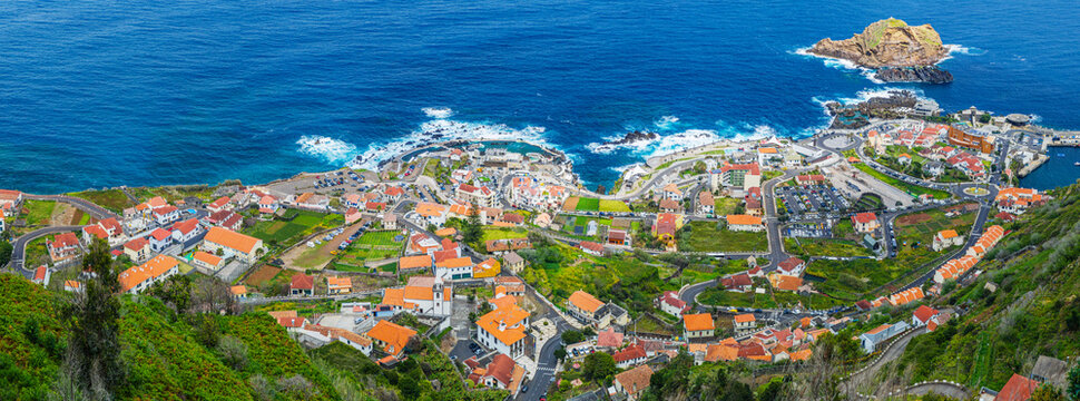 A breathtaking high-angle view of the seaside town of Porto Moniz stretching along the rugged Atlantic ocean coast, Madeira, Portugal.