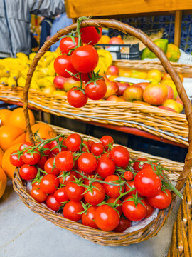 Two-tier wicker baskets filled with ripe red tomatoes and yellow passion fruits at a market stand, Funchal, Madeira, Portugal.