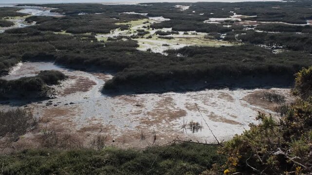 4K traveling shot of the Auray River estuary, Brittany, France, at low tide. Vertical movement from bottom to top over textured marshlands, mudflats, and salt meadows.