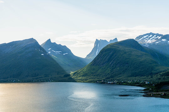 Iconic Okshornan mountain peaks behind Bergsfjorden with sun reflection in Senja Norway
