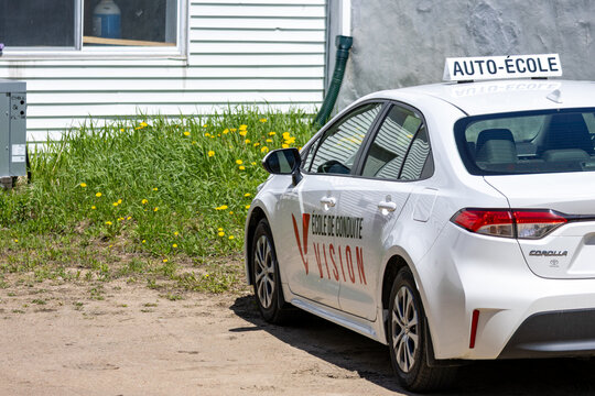La Tuque, Quebec, 23 May 2026 : White Toyota Corolla driving school car with "Auto-Ecole" sign and "Ecole de Conduite Vision" branding.