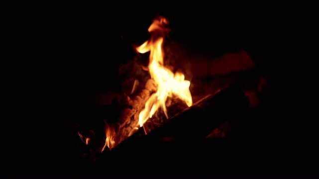 Close-up of a campfire burning brightly in the dark. Flames dance and flicker, creating a warm and inviting atmosphere, perfect for camping, adventure, or any project needing primal energy.