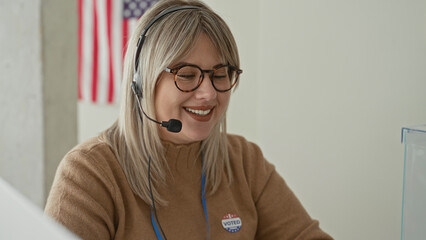 Naklejka premium Woman speaking into headset, wearing glasses and 'voted' sticker at a polling station building; civic pride.