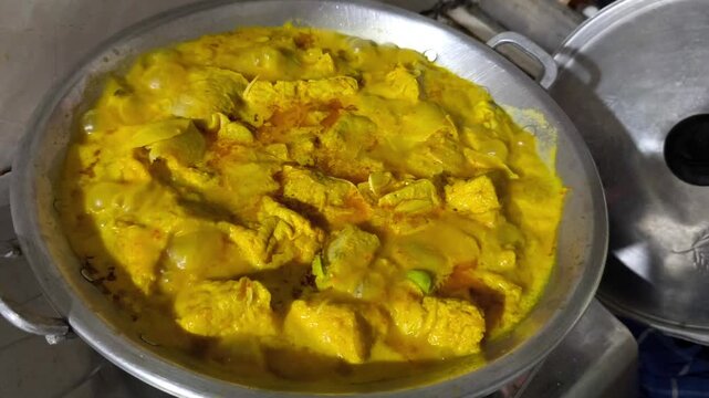 Boiling Indonesian yellow curry with tofu tempeh and petai in a wok