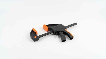 Naklejka premium Sturdy black and orange trigger clamp tool designed for professional woodworking projects and home repair tasks