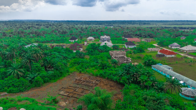 Aerial view of scattered houses, lush vegetation, palm trees, and building foundations in a rural landscape, Minima, Rivers, Nigeria.