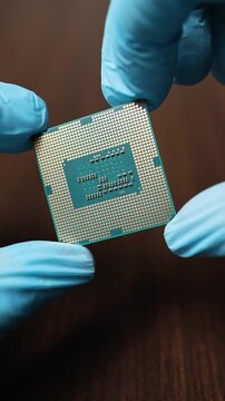 Close up view of hands in blue gloves holding CPU microchip module. Concept of global semiconductor shortage, high tech microelectronic component deficit and artificial intelligence development.