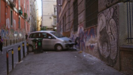 Narrow city alley with graffiti facades, bollards and parked van in soft defocused bokeh  background backplate copyspace. © Krakenimages.com
