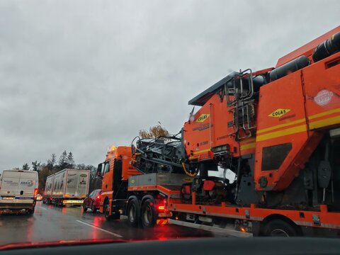 Prague,Czech Republic-April 2 2026: Colas road paver transported on a low loader trailer along a highway to a construction site