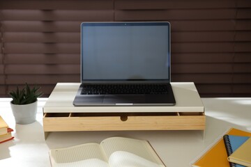 Fototapeta premium Workplace with laptop on riser stand and stationery indoors, closeup