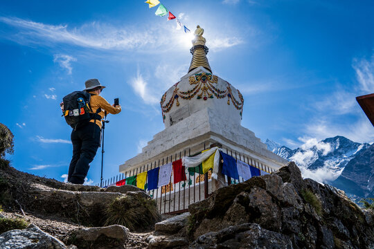 Mujer senderista tomando una foto de una estupa budista, en su camino al Everest Base Camp, en Nepal