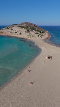 Bright sun and crystal-clear waters highlight Simos Beach on Elafonisos Island. Sandy shores invite relaxation while gentle waves lap against the land, creating a serene escape in Greece.