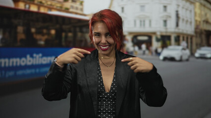 Fototapeta premium Woman points finger to chest on a busy city street near a red bus, smiling warmly; self confidence empowerment.