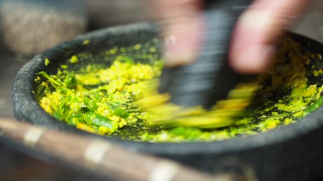 Traditional Asian Cooking: Hand Grinding Green Chili and Spice Paste in Stone Mortar and Pestle