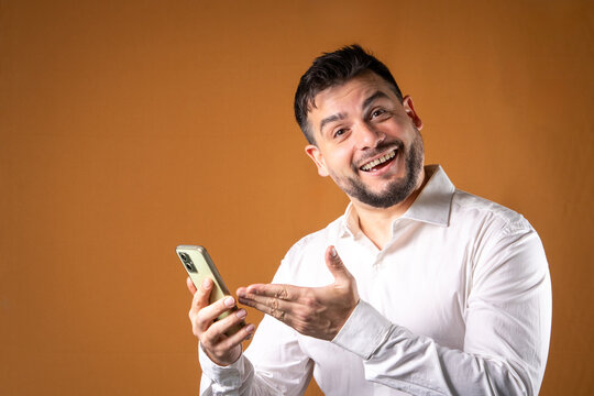 Hombre sonriente y exitoso mostrando su tel&eacute;fono. Ideas para comunicaciones y atenci&oacute;n