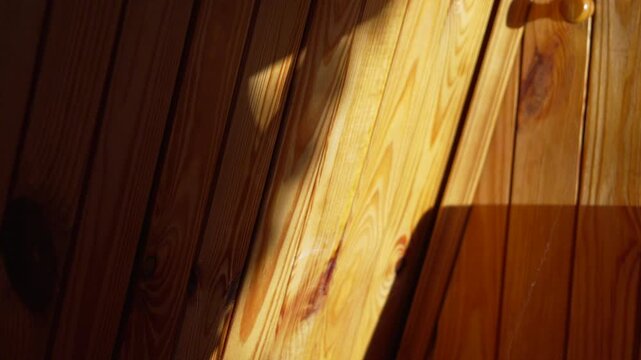 Wood shadow sunlight flickering on a vertical pine plank wall in natural morning light creating an abstract texture