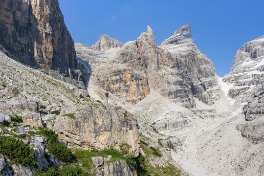 Hiker looking into a mountain valley, Castelletto Superior and Cima Sella mountain peaks, Bocca di Tuckett back, Brenta Mountains, Brenta, Brenta-Adamello Natural Park, Trentino, Italy