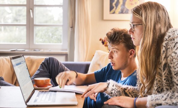 Two students sitting in front of a laptop, learning on the computer, Munich, Germany