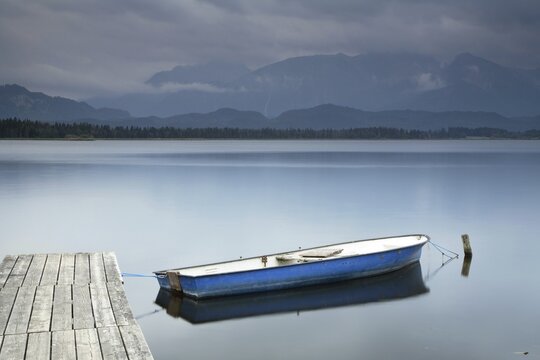 Jetty with boat at Hopfensee, behind the Allg&auml;u Alps, low hanging rain clouds, Allg&auml;u, Bavaria, Germany