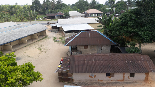 Aerial view of a rural settlement with simple houses featuring corrugated metal roofs, surrounded by lush tropical vegetation and trees in Minima, Rivers, Nigeria.