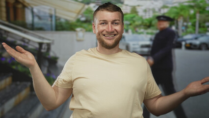 Fototapeta premium Man waving right hand and smiling broadly on a busy street with parked cars and steps visible; casual joy.