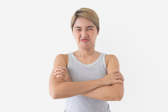 Young Thai woman showing strong disgust, grimacing with a wrinkled nose and crossed arms.
