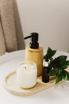 Still life of luxury spa essentials. A glass bottle with a serum, bottle with oil and candle on a table.