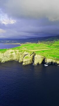 Rocky sea cliffs and coastline on Azores island in Atlantic Ocean. Aerial wide view with rural fields above cliffs