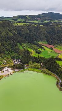 Volcanic crater lake in green landscape with rural surroundings, aerial view, Furnas Azores Portugal