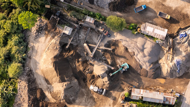 Aerial view of a sand and gravel mining site with conveyor belts, heavy machinery, and piles of aggregate in Indonesia.
