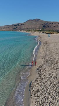 Enjoy the breathtaking vistas of Simos Beach in Elafonisos Island Greece. Experience vibrant blue waters, golden sands, and sun-kissed shores where visitors stroll along the serene coastline.