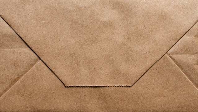 Brown kraft paper bag bottom background with geometric folds and edge texture.