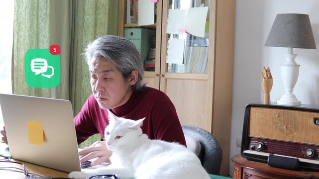 White haired mature Asian man using laptop at home with his cat, featuring a 3D tracked double speech bubbles messenger chat notification pop up and red counter.