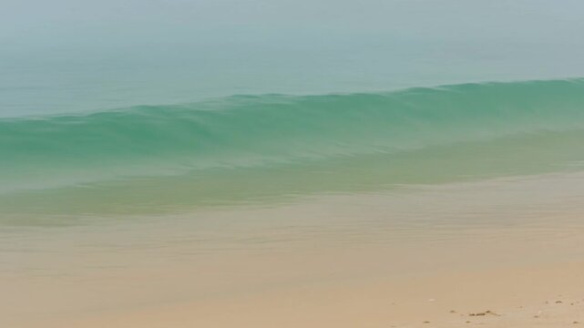 Turquoise Ocean Wave Rolling Onto Sandy Beach