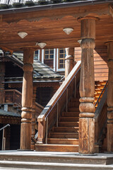 Naklejka premium Wooden staircase ascends to an upper level, framed by large wooden columns in a rustic architectural environment with ample natural light