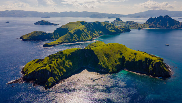 Aerial view of Komodo National Park with lush green hills surrounded by deep blue sea in East Nusa Tenggara, Indonesia.