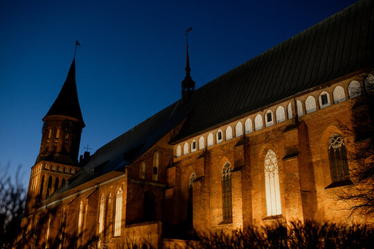 Cathedral on Kant Island in Kaliningrad, featuring Gothic architectural elements and illuminated stained glass windows during twilight hours