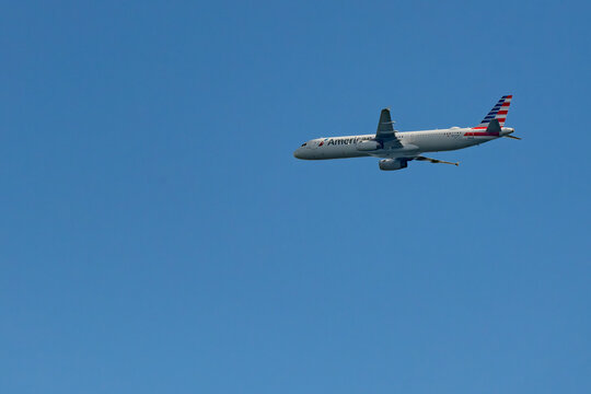 An American Airlines Airbus A321 plane flies isolated against a blue sky with copy space