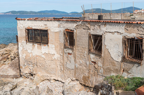The abandoned structure located in Alghero, Sardinia, Italy, along the Dante seafront wall.