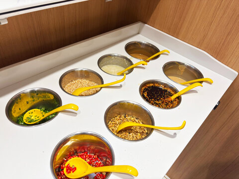 A hot pot condiment bar with a wide variety of sauces, spices, and toppings neatly arranged for diners to customize their meals.