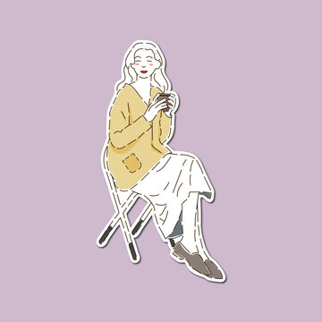 A woman wearing a yellow cardigan and skirt is sittig holding a cup